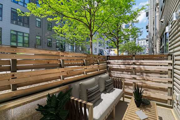 A wooden bench with a cushion and a pineapple on a table in a sunny outdoor area.