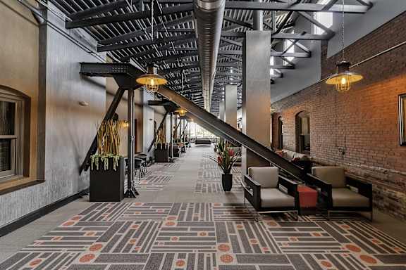 a lobby with a large staircase and a rug on the floor at The Knights @ 506 Delaware Apartments, New York 14202
