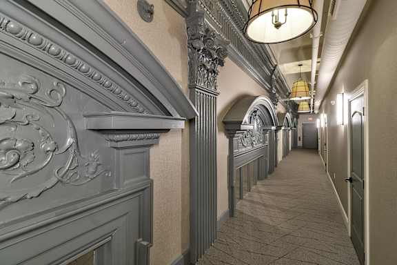a long hallway with a long row of columns and a ceiling light at The Knights @ 506 Delaware Apartments, NY 14202