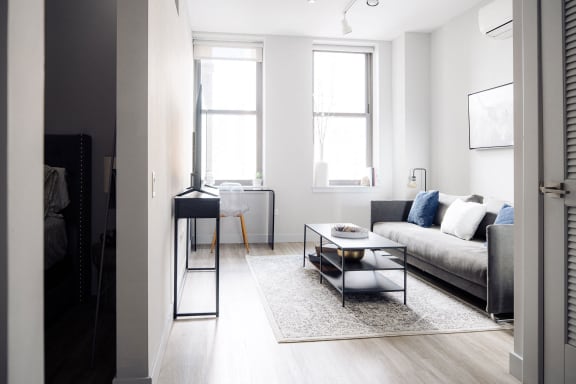 a living room with a couch and a coffee table    and two windows
