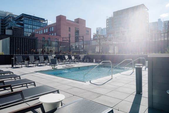 a pool on the rooftop of a building with a city in the background