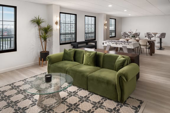 a living room with a green couch and a glass coffee table  at Vision on Lombard, Baltimore, MD