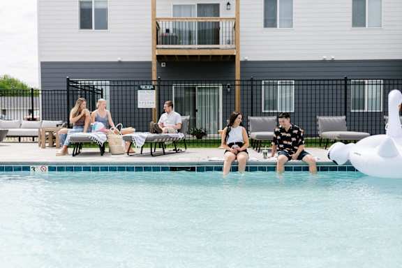 a group of people sitting around a swimming pool