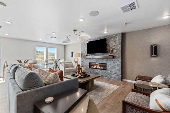 A modern living room with a grey couch, a fireplace, and a flat screen TV mounted on the wall.