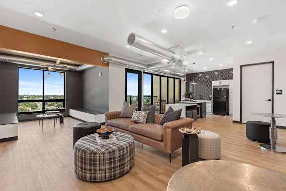 A modern living room with a brown couch and a checkered ottoman.