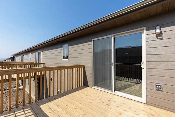 A wooden deck leads to a sliding glass door.