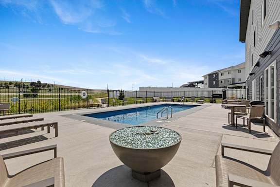 A pool with a fountain in the middle of a patio.
