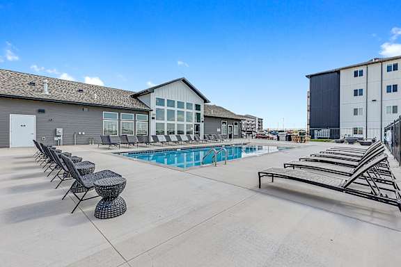 A pool area with sun loungers and a building in the background.