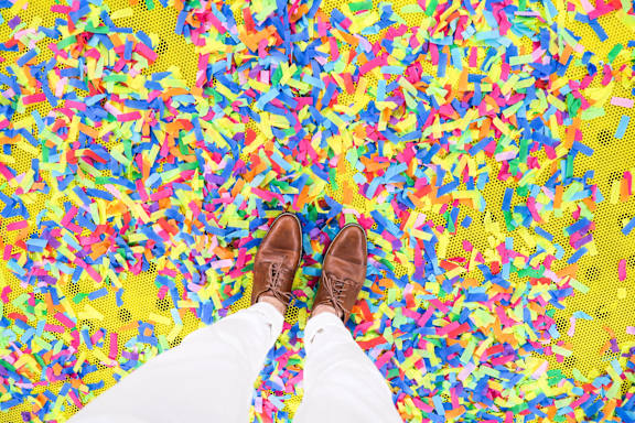 a man standing on a colorful confetti floor with his shoes