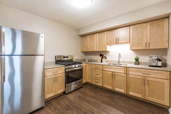 A kitchen with wooden cabinets and a stainless steel refrigerator.