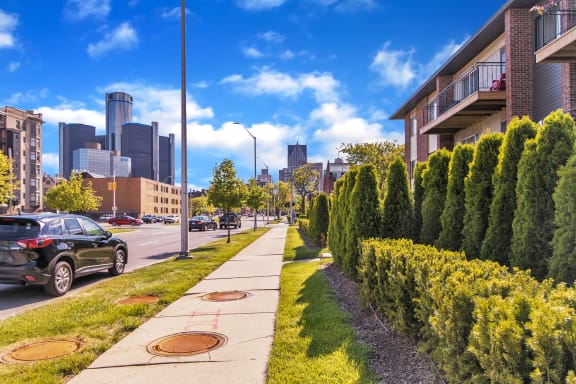 a city street with a row of trees on the left and a city in the background at Lafayette Park Place, Detroit, MI, Detroit, MI