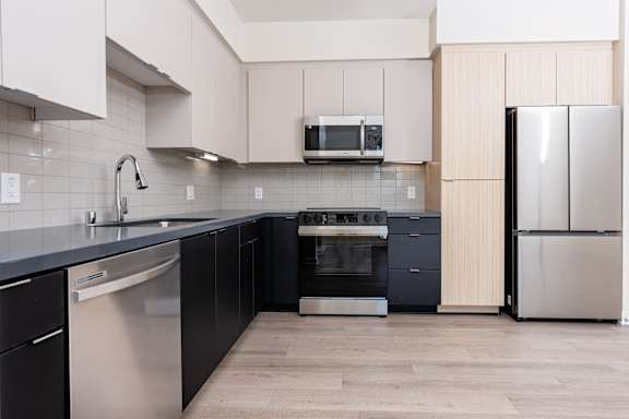 A kitchen with black and white appliances and wooden cabinets at North Grove Apartments, Riverside