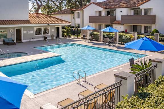 A swimming pool surrounded by blue umbrellas and chairs.