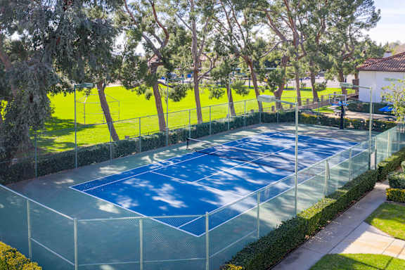 A tennis court surrounded by a fence and trees.
