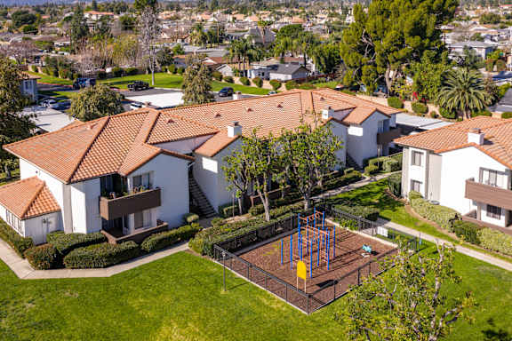 A playground with a swing set is in the front yard of a house.