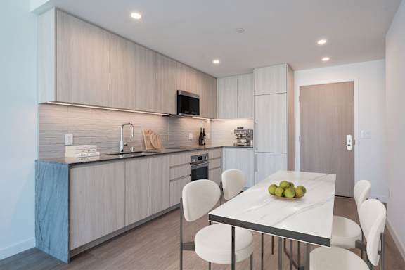 A modern kitchen with a dining table set with fruit.