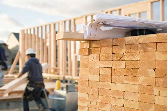 a construction site with stacks of wood and a worker working on it