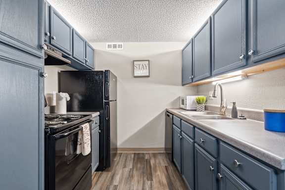 A kitchen with dark wood cabinets and a black refrigerator.