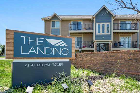 A sign for The Landing at Woodlawn Tower in front of a building.