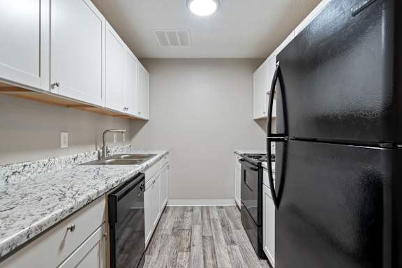 an empty kitchen with white cabinets and a black refrigerator