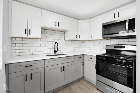 a white kitchen with white cabinets and black appliances