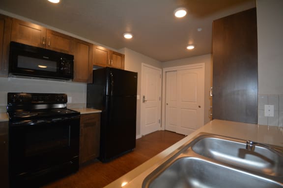 Image of kitchen sink, microwave, refrigerator, stove and cabinets