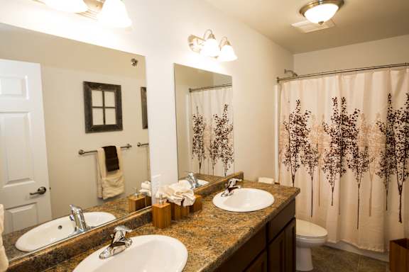 Image of two sinks, toilet, two mirrors and bathtub
