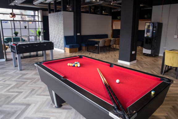 a red pool table in a room with other tables and chairs