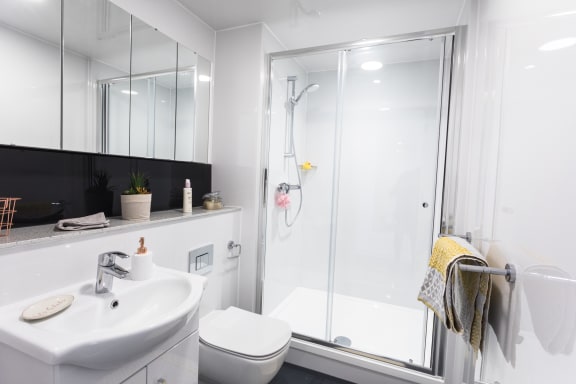 a bathroom with a white sink and toilet next to a shower with a glass door