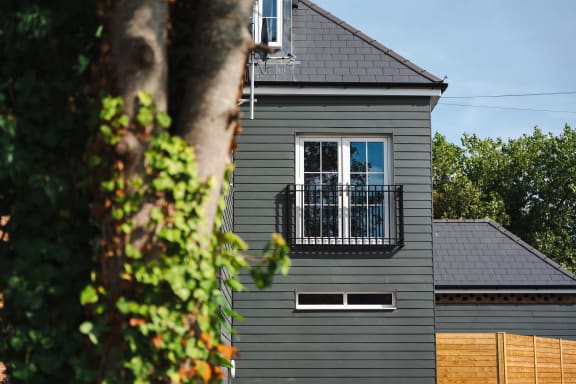 a gray house with a balcony and a window