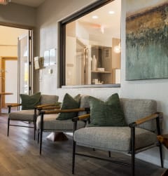 a living room with chairs and a painting on the wall