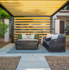 a patio with a couch and a chair under a wooden structure