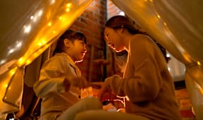 two girls sitting in a tent with lights