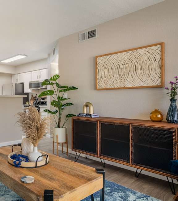 A modern living room with a grey sofa, wooden coffee table, and a large abstract art piece on the wall.