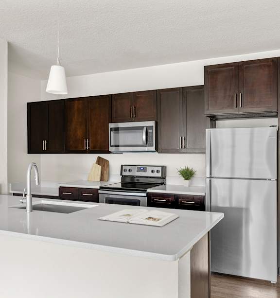 A kitchen with a refrigerator, oven, and sink.