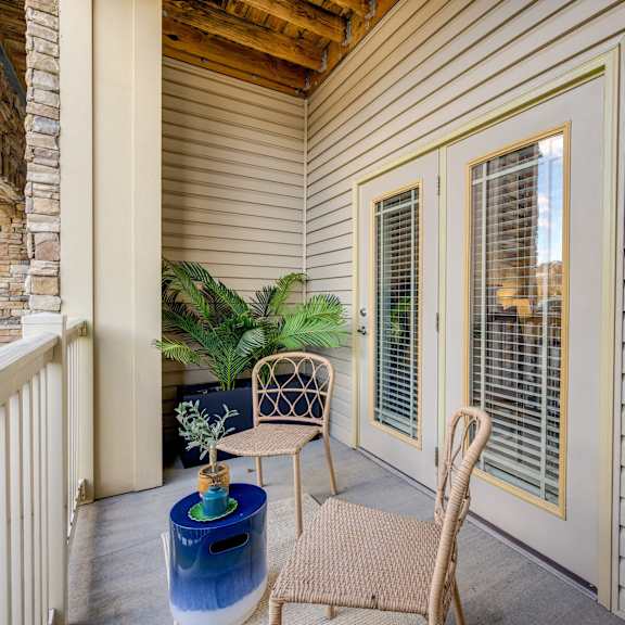 A patio with a chair, table, and potted plant.