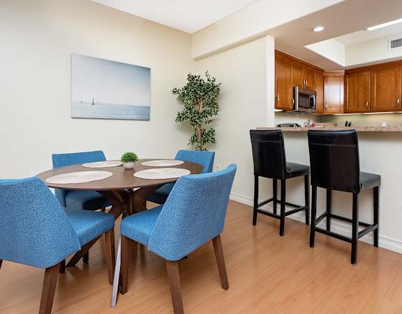 a dining area with a table and chairs and a kitchen in the background