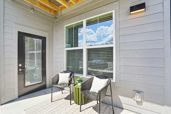 A patio with two chairs and a table with a green cushion.