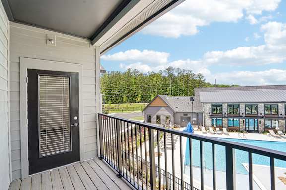 A balcony with a view of a pool and a building.