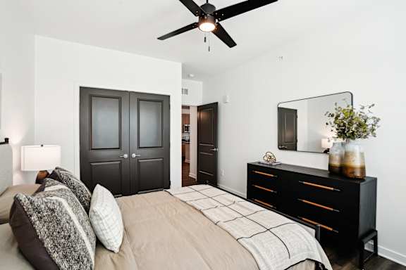 A bedroom with a bed, dresser, and ceiling fan.