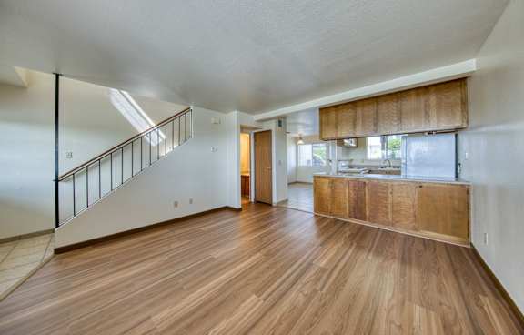 A spacious room with wooden floors and a staircase.