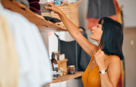 a woman reaching for a shirt on a shelf in a closet at Sunset Barrington Gardens, Los Angeles, CA