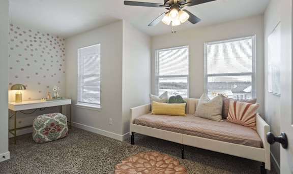 A bedroom with a bed, a window, and a ceiling fan.