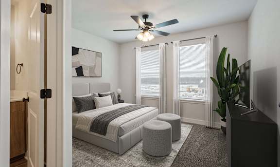 A bedroom with a bed, a ceiling fan, and a window with blinds.