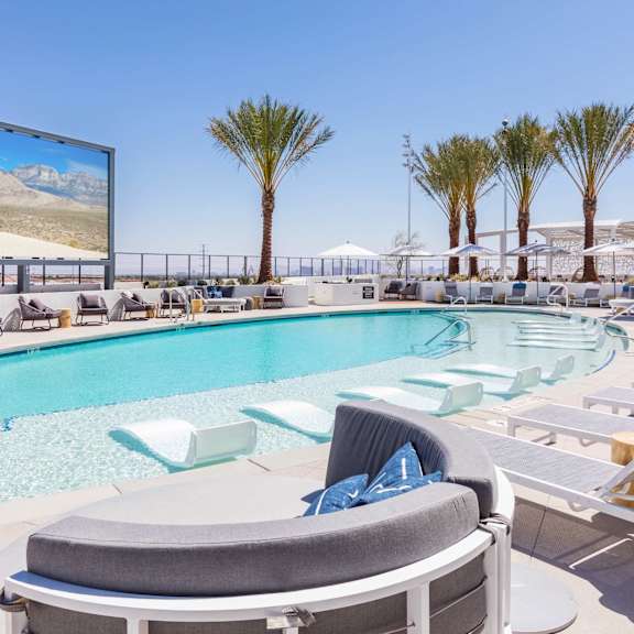 A large screen is mounted on a wall above a pool.