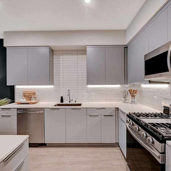 A modern kitchen with a black countertop and white cabinets.