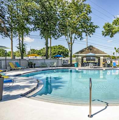 a resort style pool with lounge chairs and a gazebo at Fusion Apartments, Orlando