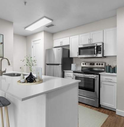 A modern kitchen with white cabinets and stainless steel appliances.