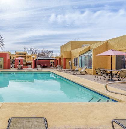 A large outdoor swimming pool surrounded by lounge chairs and umbrellas.