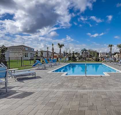 A swimming pool surrounded by lounge chairs and palm trees.